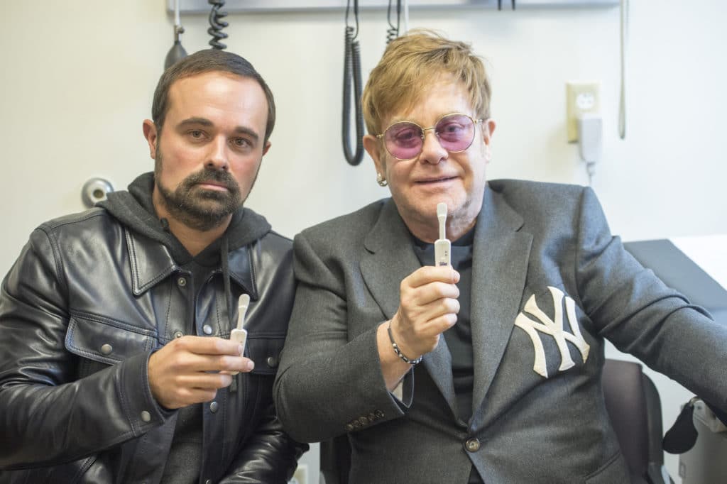 Elton John holds up an oral HIV test.