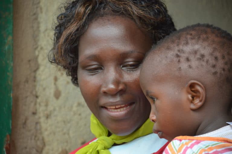 Mother who has been impacted by HIV looks lovingly at her young child.