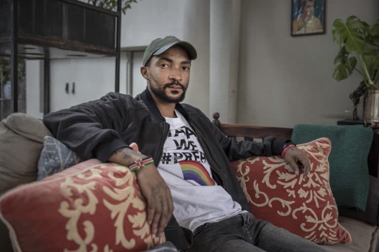 Phumlami from Johannesburg is a member of the LGBTQ+ community. He sits wearing a t-shirt that promotes safe sex messaging for PrEP.