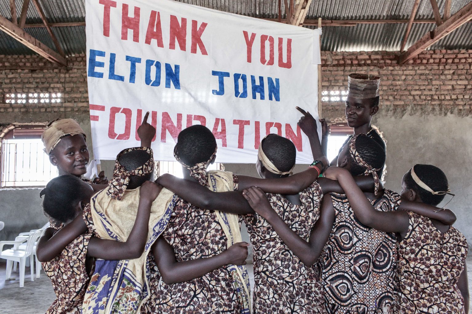 Young people in Kenya who are living with HIV hold up a sign that says 'Thank you Elton John Foundation'.