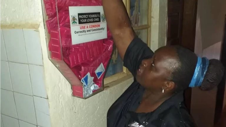 Tukei refills a condom dispenser at a local hotspot in Uganda to give female sex workers in the community access to HIV prevention.