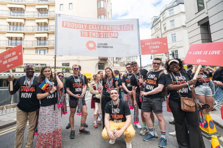 Elton John AIDS Foundation team at London Pride with statement banner and placards.