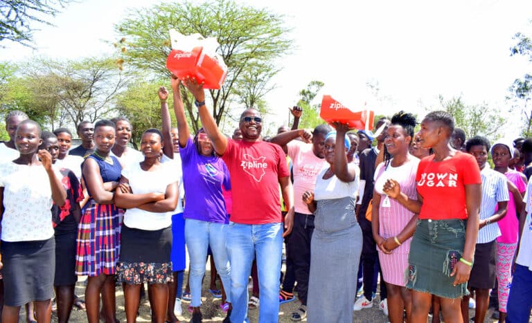 Zipline representative and community members celebrating the delivery of a medical supplies..