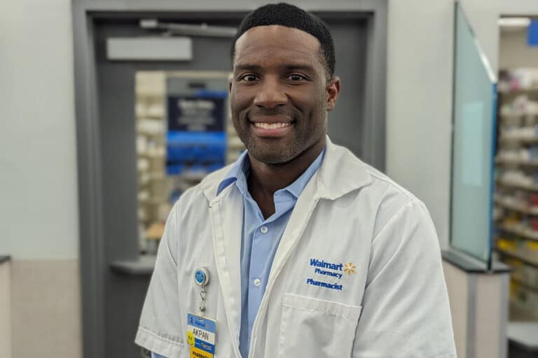 Dr. Akpan, Pharmacy Manager at a Walmart store in Atlanta, wearing his pharmacist uniform.