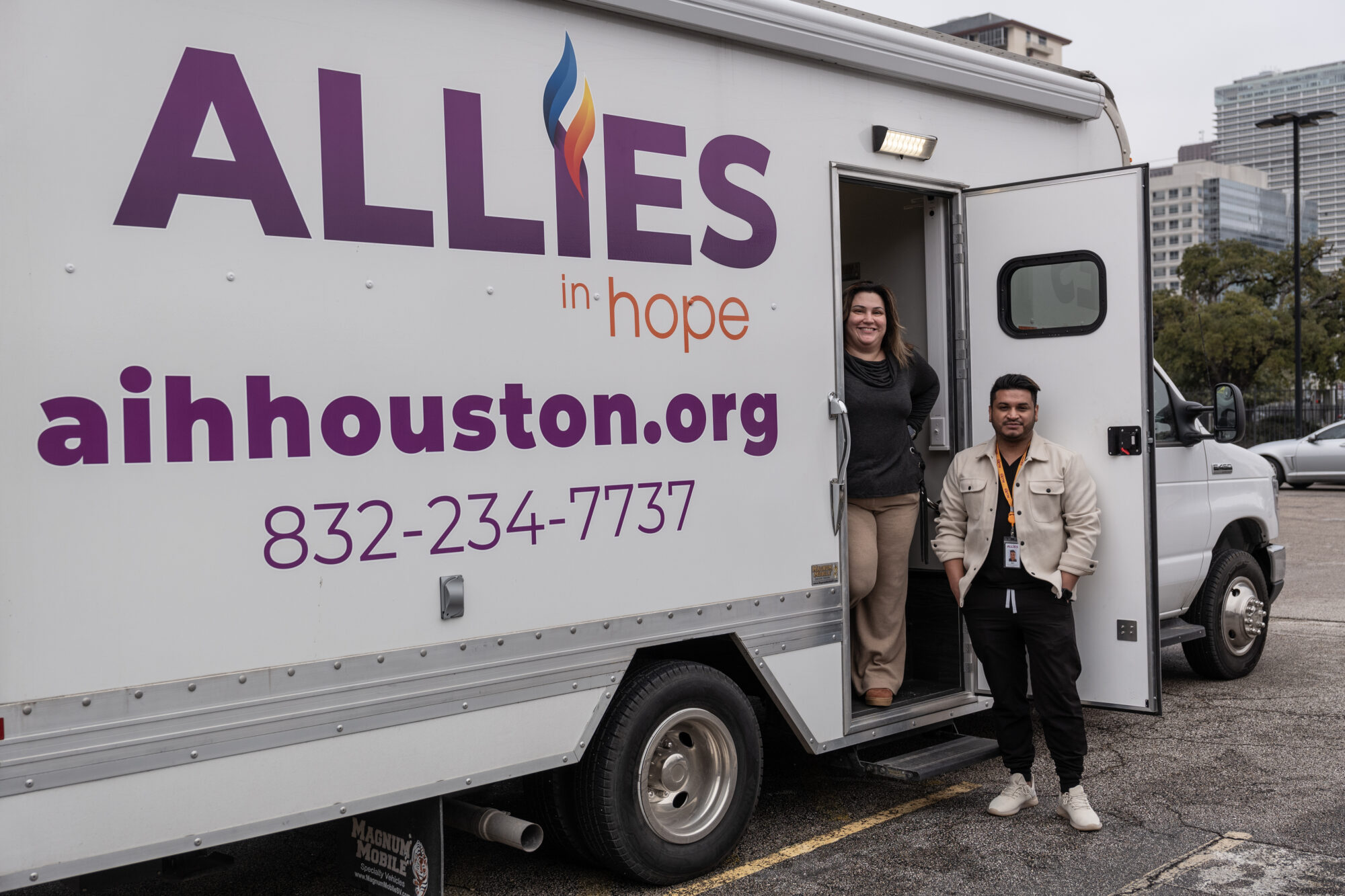 Two Allies in Hope employees stand beside their mobile health unit which provides HIV testing and information around Houston.