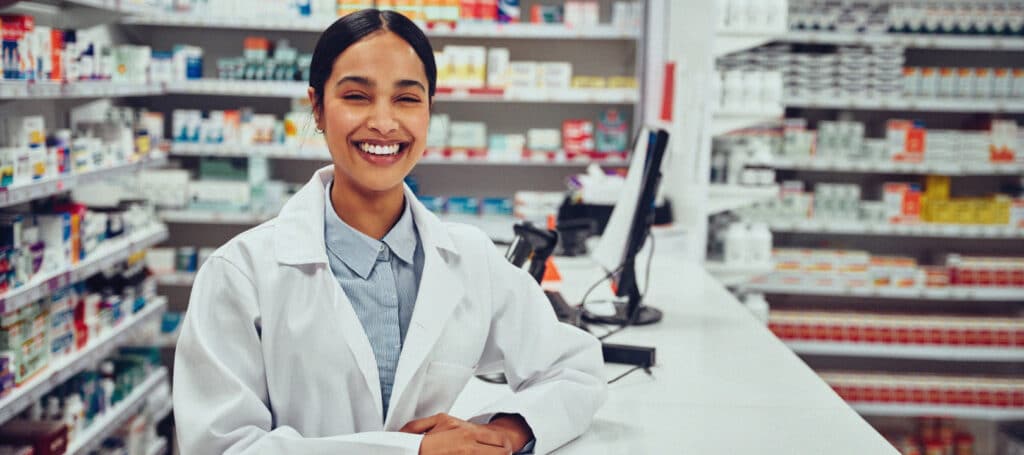 Female pharmacist smiles behind counter.