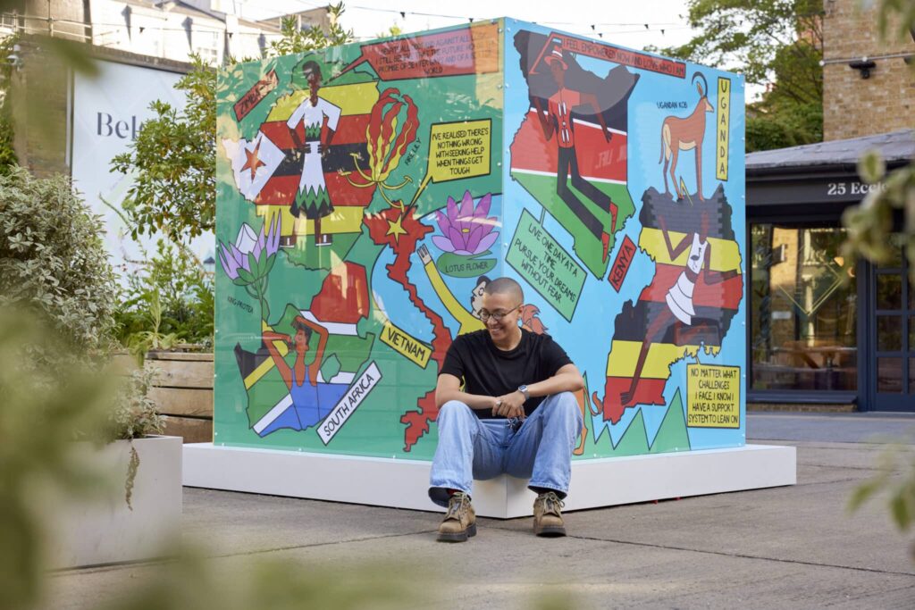 Ashton Attz sits in front of their illustrative installation in Ecclestone Yards.