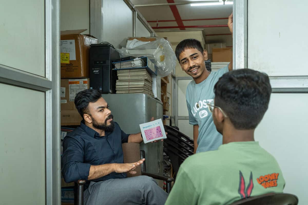 Three people talking in a space. Two are facing the camera, and the client has their back to the camera.